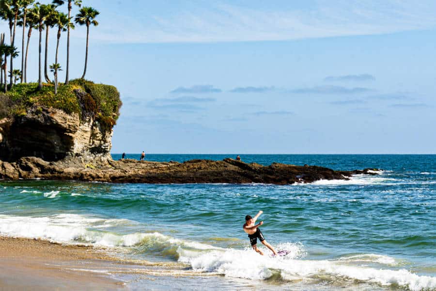 A man skimboarding near the shore in Laguna Beach