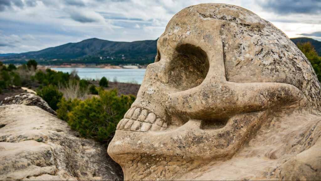 A stone skull sculpture at the Route of the Faces of Buendía