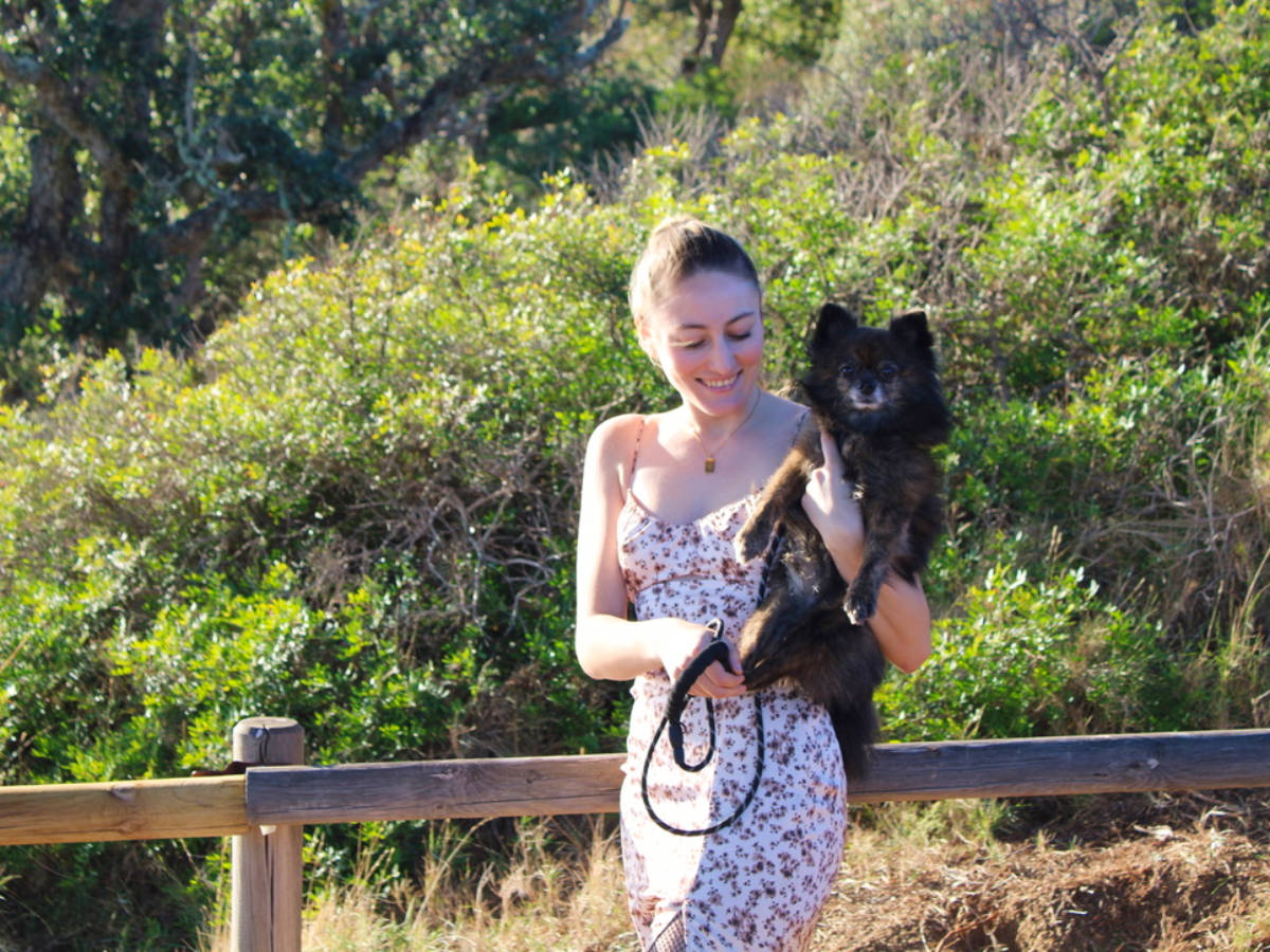 The author Sky Ariella holding her dog with the greenery in the background