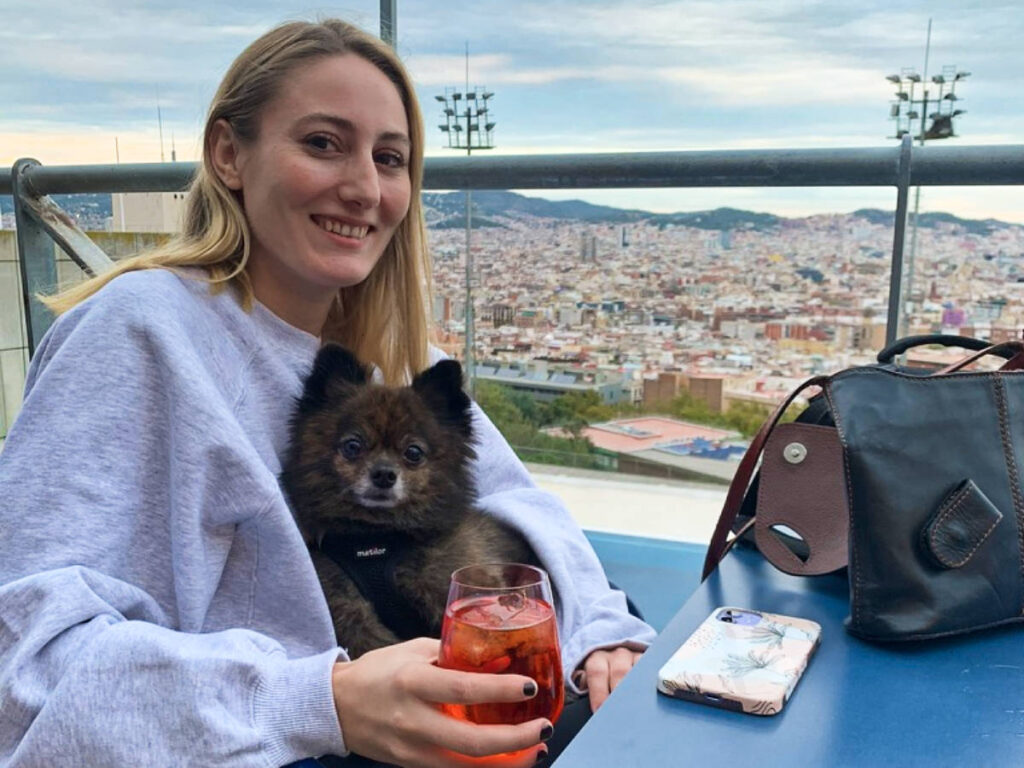 Travel Lemming Writer Sky Ariella, drinking at a rooftop bar with her dog on her lap