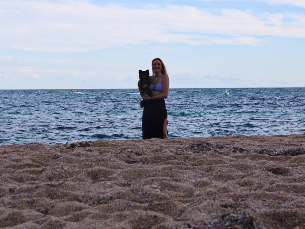Travel Lemming Writer Sky Ariella and her dog, Bear, posing along the shoreline on the beach in Blanes