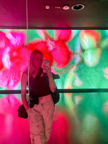 Travel Lemming Senior Writer Sky Ariella posing for a photo inside the colorful interior of Moco Museum