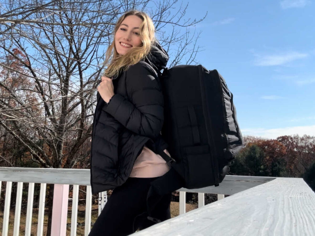 The author Sky Ariella wearing and showing her Topo Designs Global Travel Bag