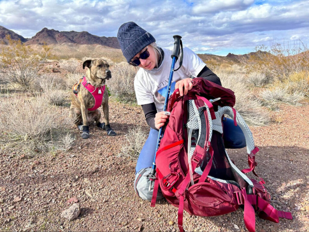 Skycie setting up her Osprey Aura AG LT 65 with her dog on her background