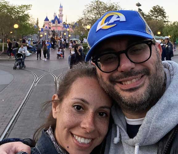 The author's family member smiling for a selfie in front of the Sleeping Beauty’s Castle