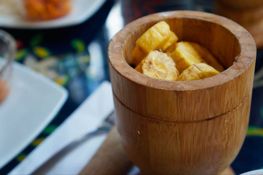 Sliced banana on a pestle with a mortar beside it