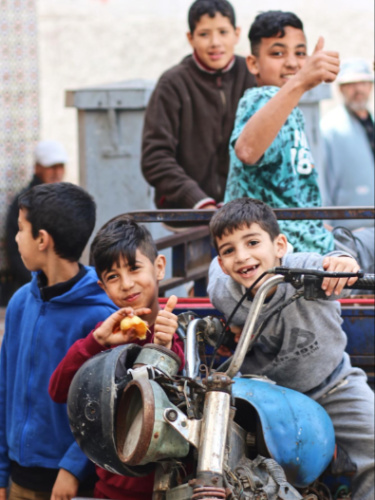 Group of kids smiling while riding on a motorbike