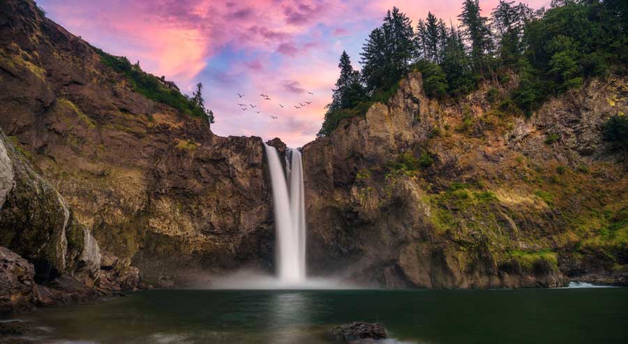 The Snoqualmie Falls and the colorful sky above it during sunset