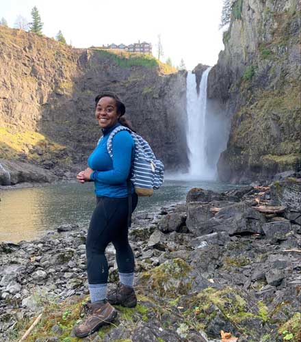 The author smiling for a photo with the Snoqualmie Falls on her background