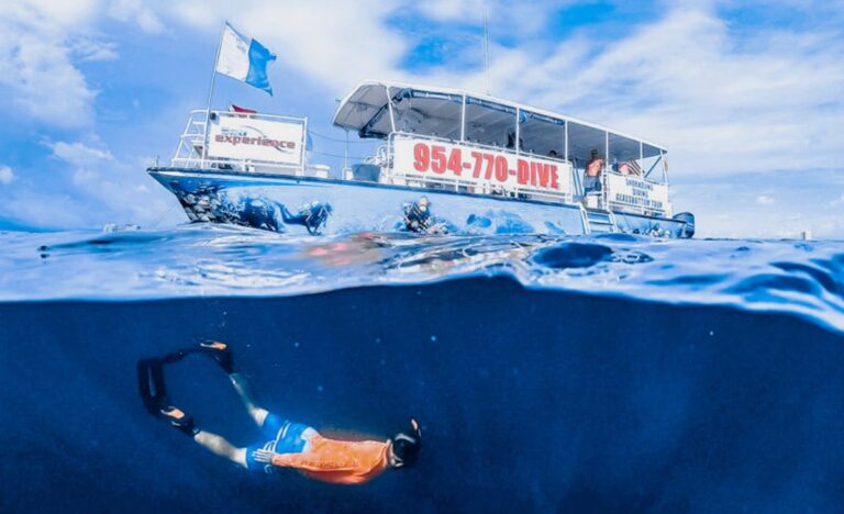 A man snorkeling in clear ocean waters, with a boat visible in the background
