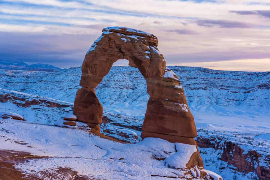 View of the famous Delicate Arch covered in snow at dusk
