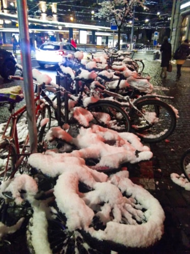 View of the bicycles covered with snow on the side of the street