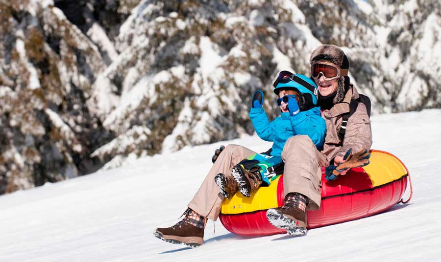 A woman and a kid enjoying snow tubing in Aspen