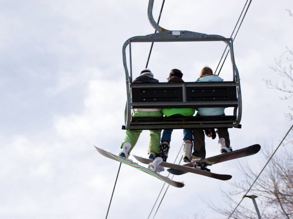 Three snowboarder friends riding the ski lift