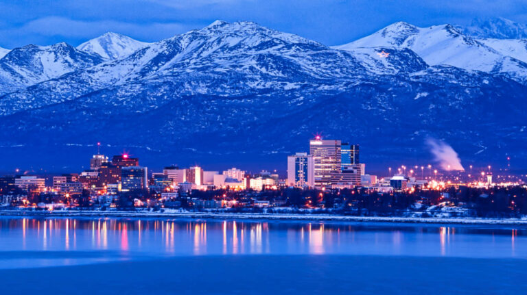 View of the Anchorage skyline with the Chugach mountains behind in winter at dusk