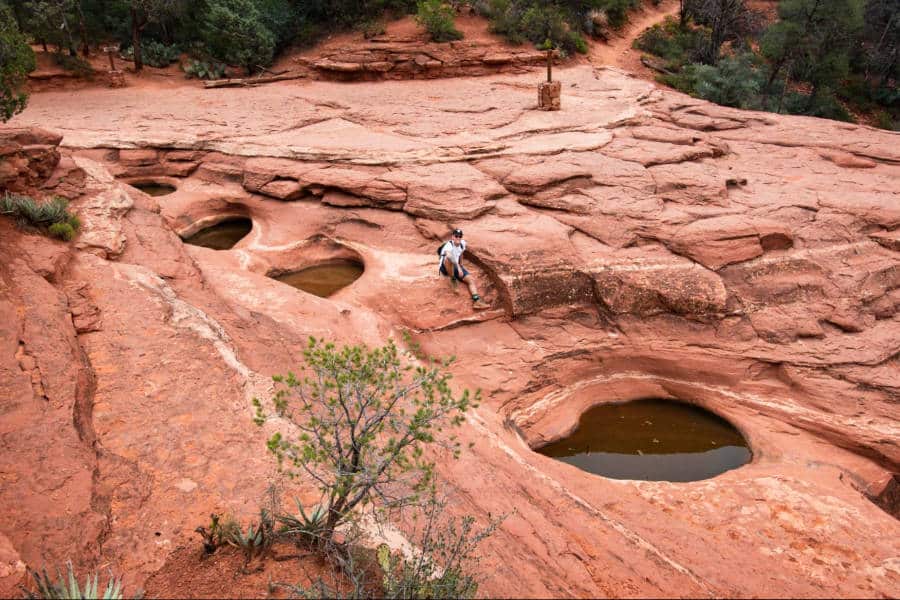 A man sitting on the ground near the small pools at the Soldier Pass Trail