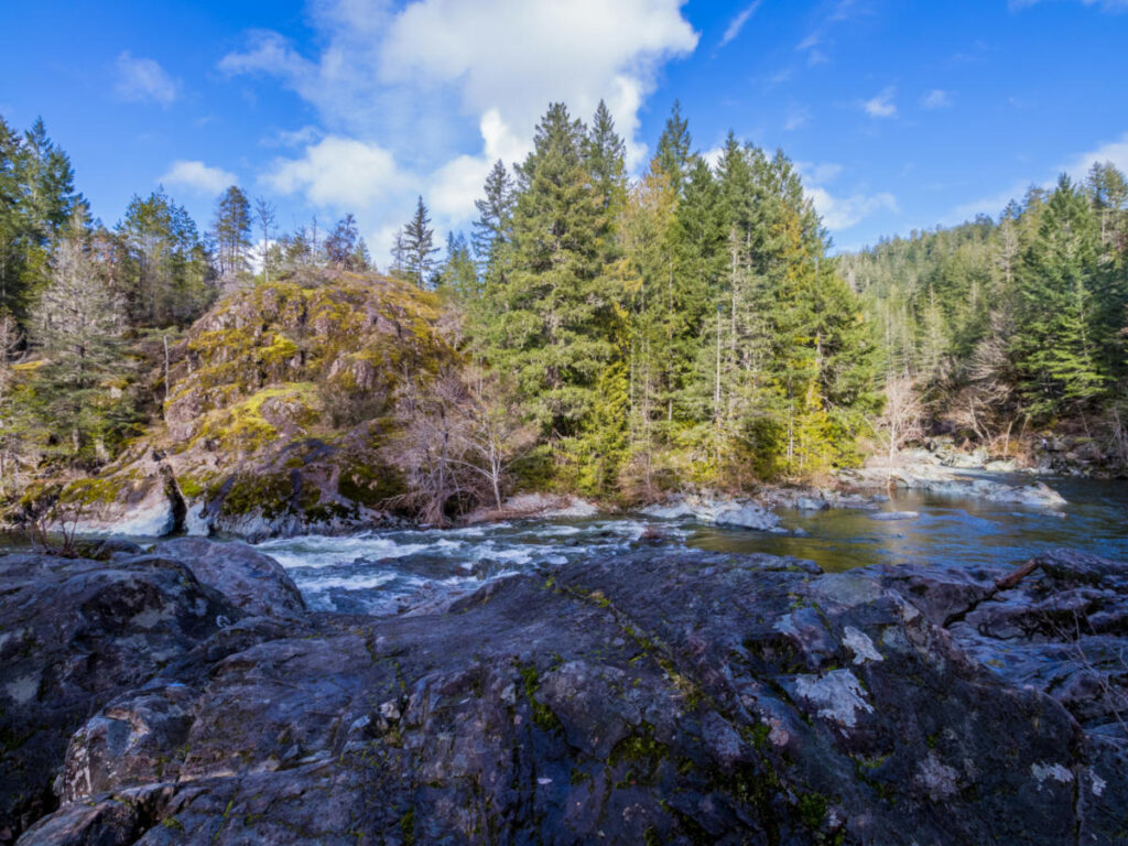 Serene river in Sooke Potholes Park, embraced by trees and rocky landscapes