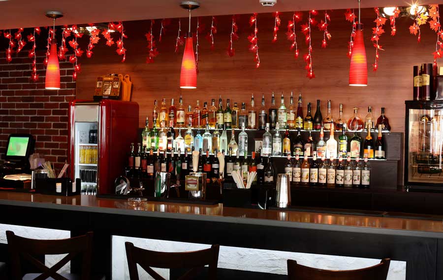 Illuminated red lights above the bar area with different drinks on the shelves and fridge