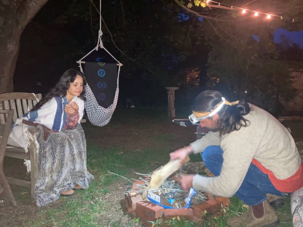 The author, McKenna Mobley with a man preparing a fire pit at night in Southampton