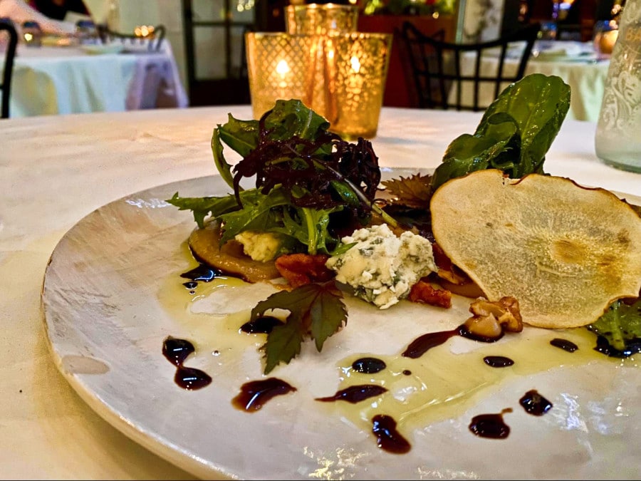 A plate of roasted pear salad with vegetables, gorgonzola cheese and sauce