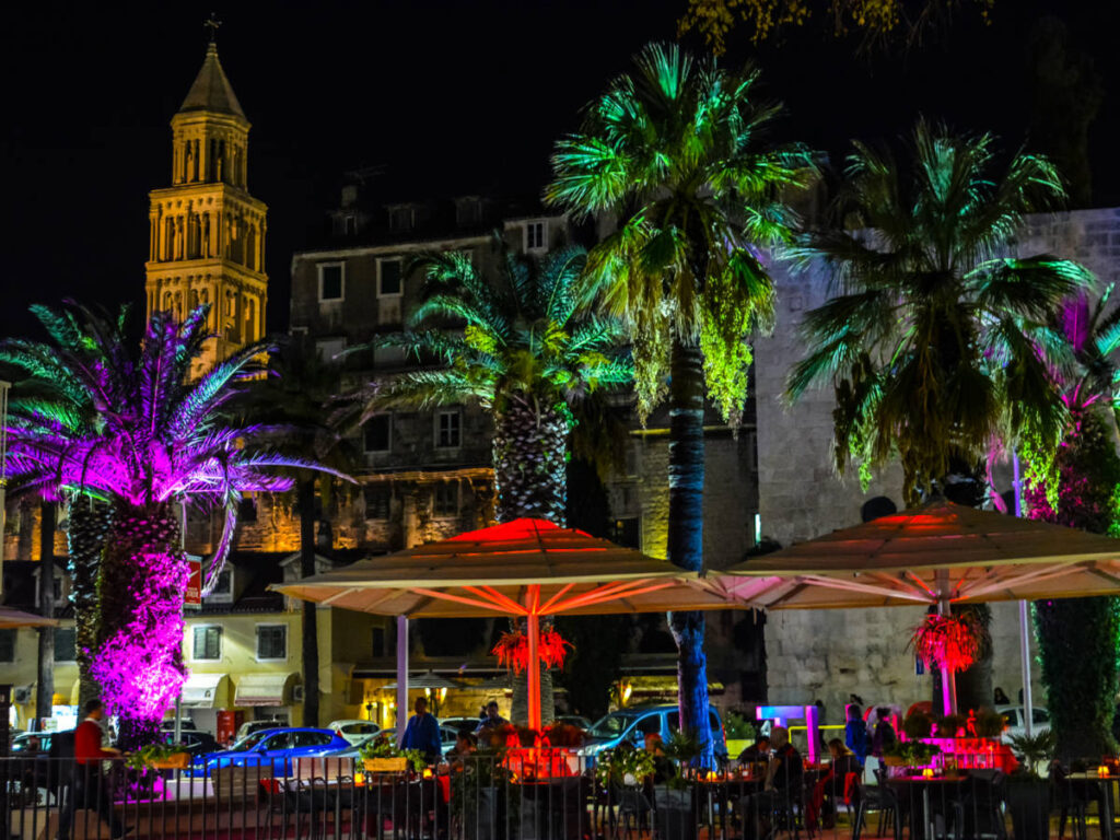 Locals and tourists at a colorful sidewalk cafe on the Riva promenade boardwalk in Split late at night
