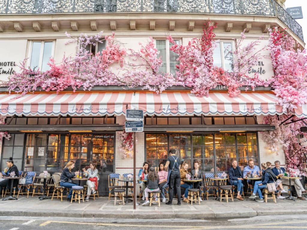 People outside a restaurant filled with cherry blossoms in Paris