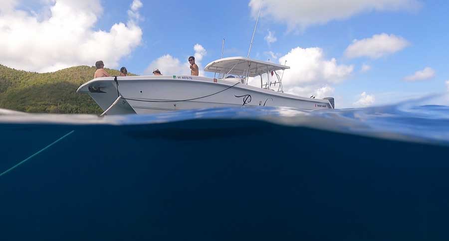 View of people on a boat while on the blue water of Maho Bay