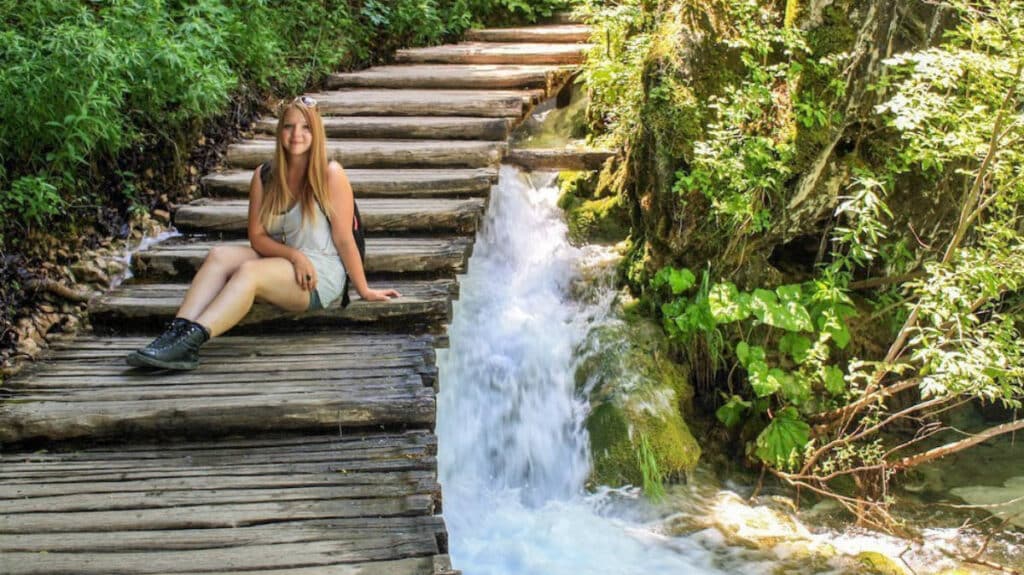Taylor Herperger sitting on a wooden staircase in Plitvice Lakes National Park