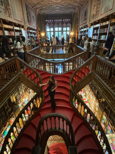 Author Sky standing at the winding staircases of Livraria Lello