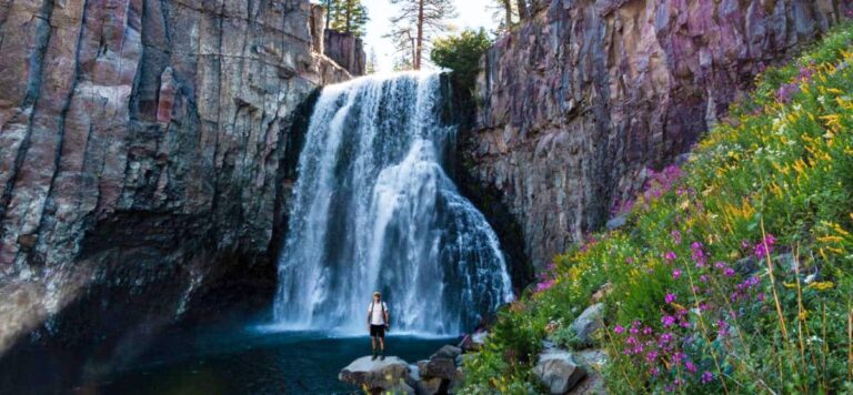 A man standing on a stone with the majestic Rainbow waterfall