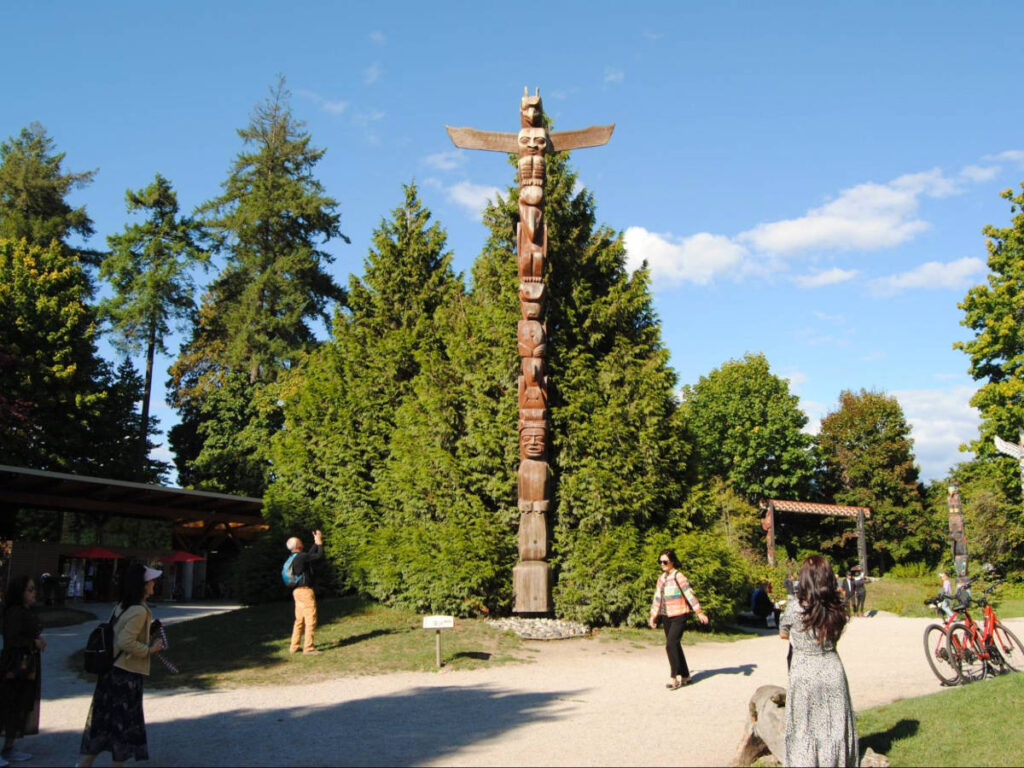People admiring the Stanley Park totem poles