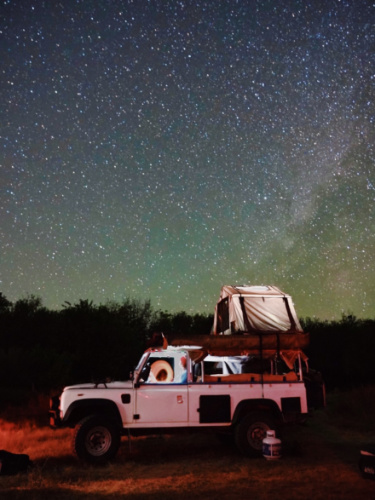 A white truck with rooftop tent under the starry sky