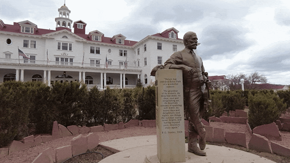 A statue leaning on a post in front of the The Stanley Hotel