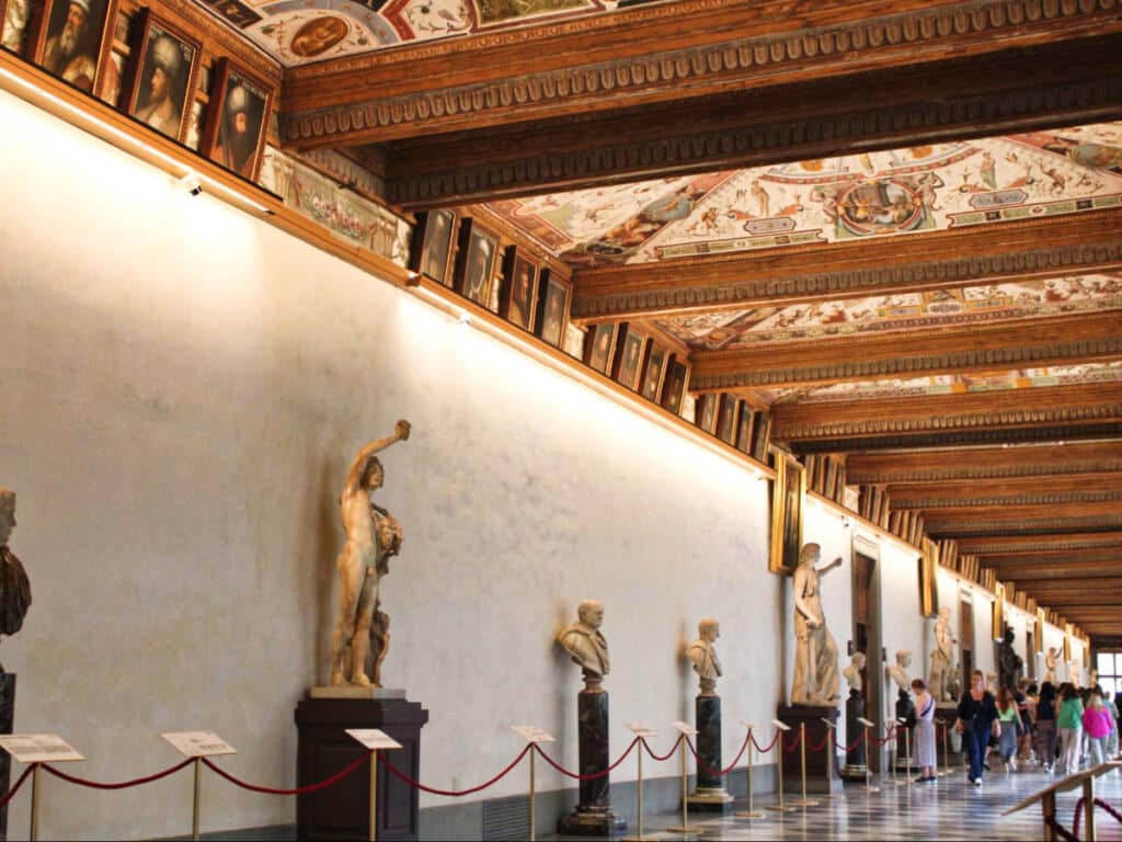 View of the people walking along the displayed statues in Uffizi Gallery 