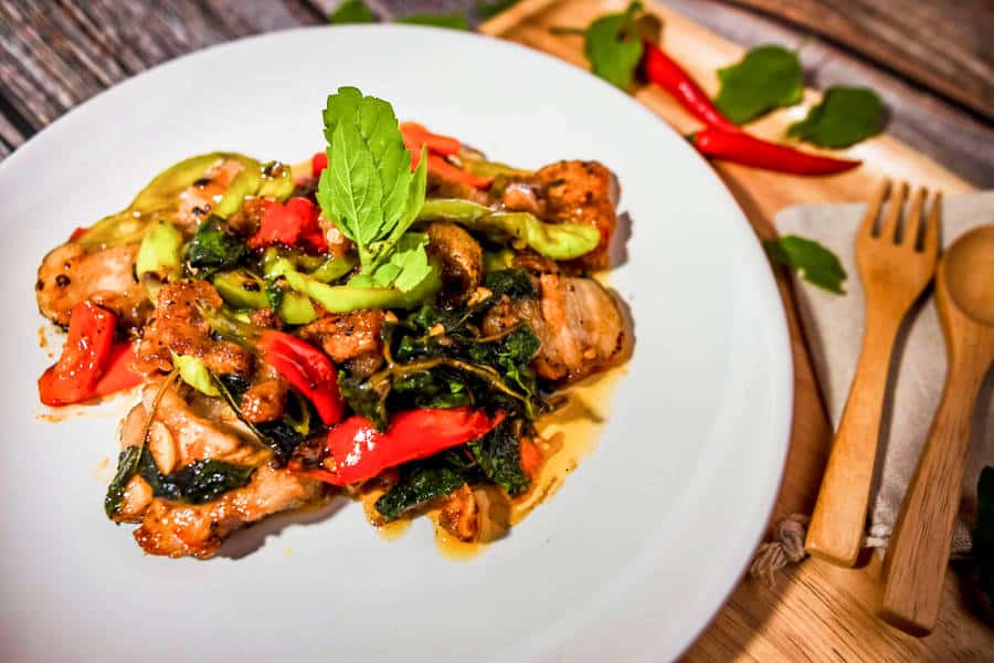 A plate of stir fried spicy crispy pork topped with Thai basil