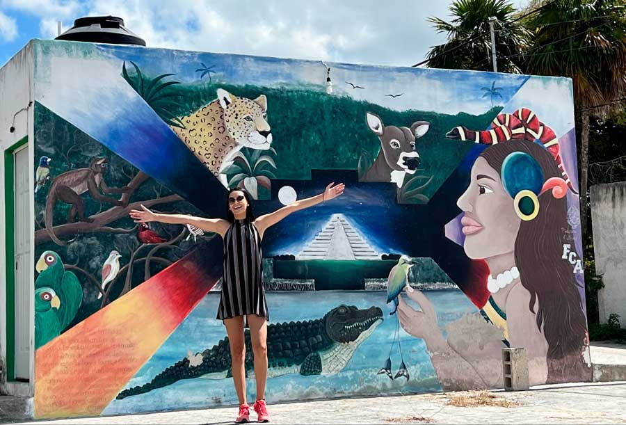 Clara posing for a photo with the street art on the wall in El Cuyo