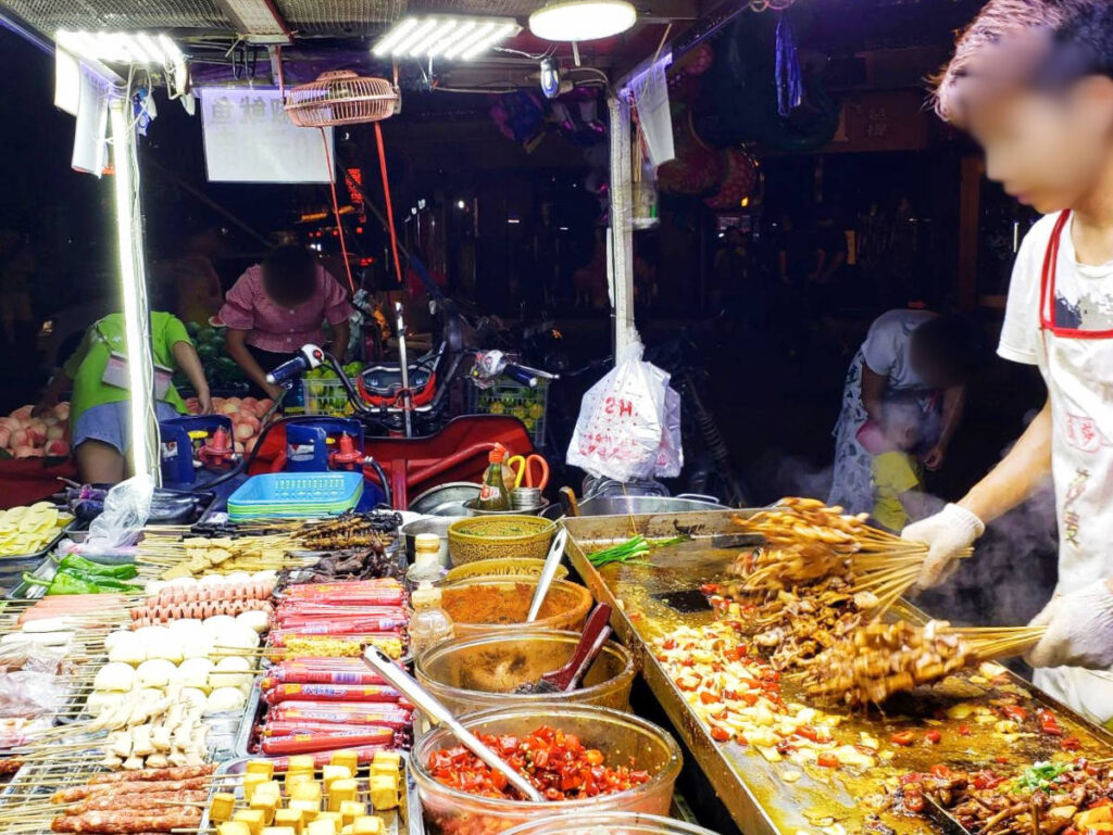A Chinese street vendor cooking a variety of skewers