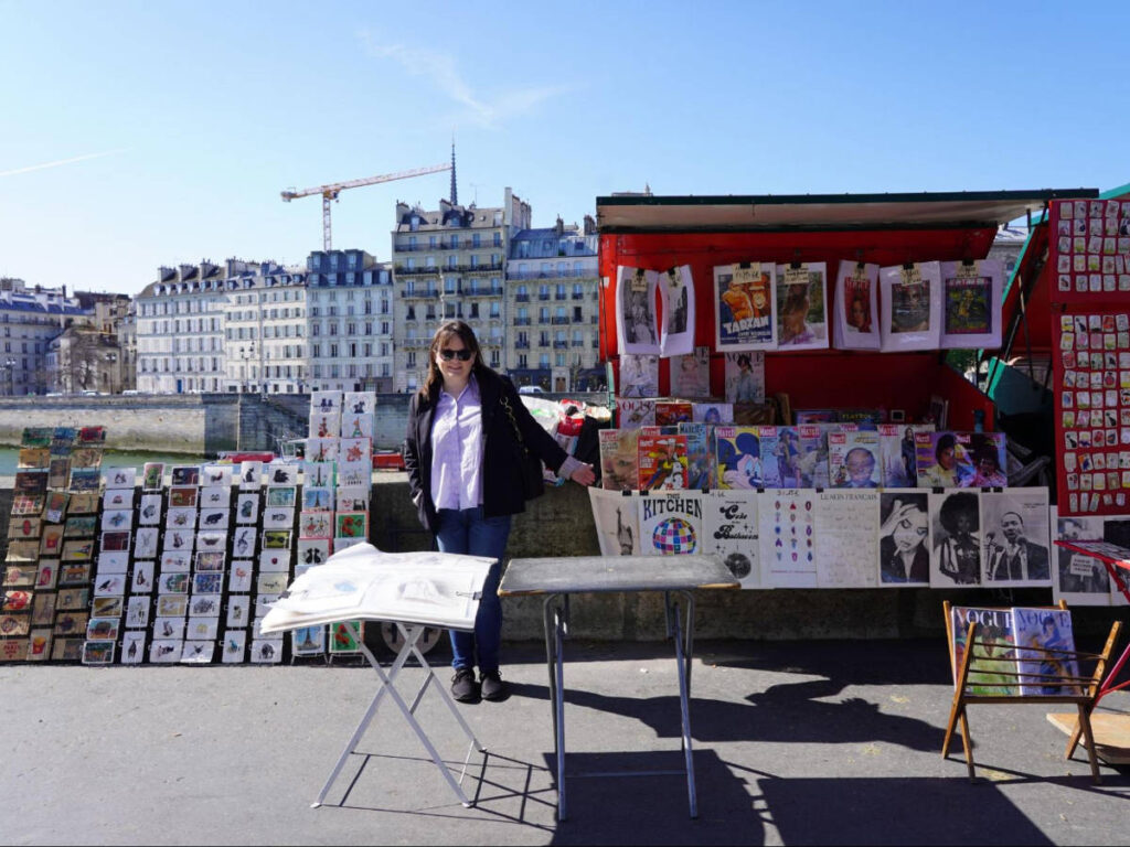 The author Rachel Kapelke-Dale smiling for a photo beside the Seine River
