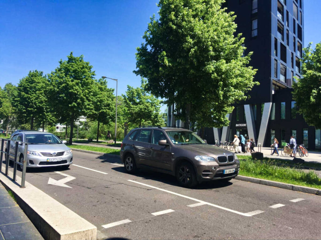View of the cars driving along the Neudorf neighborhood with the modern architecture along the street