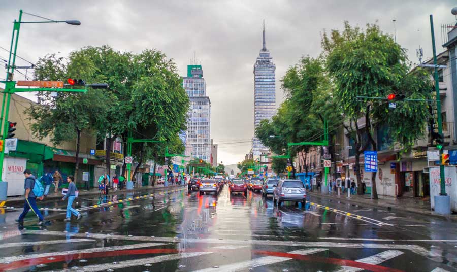 View of cars and people on a street in Mexico City during a rainy day