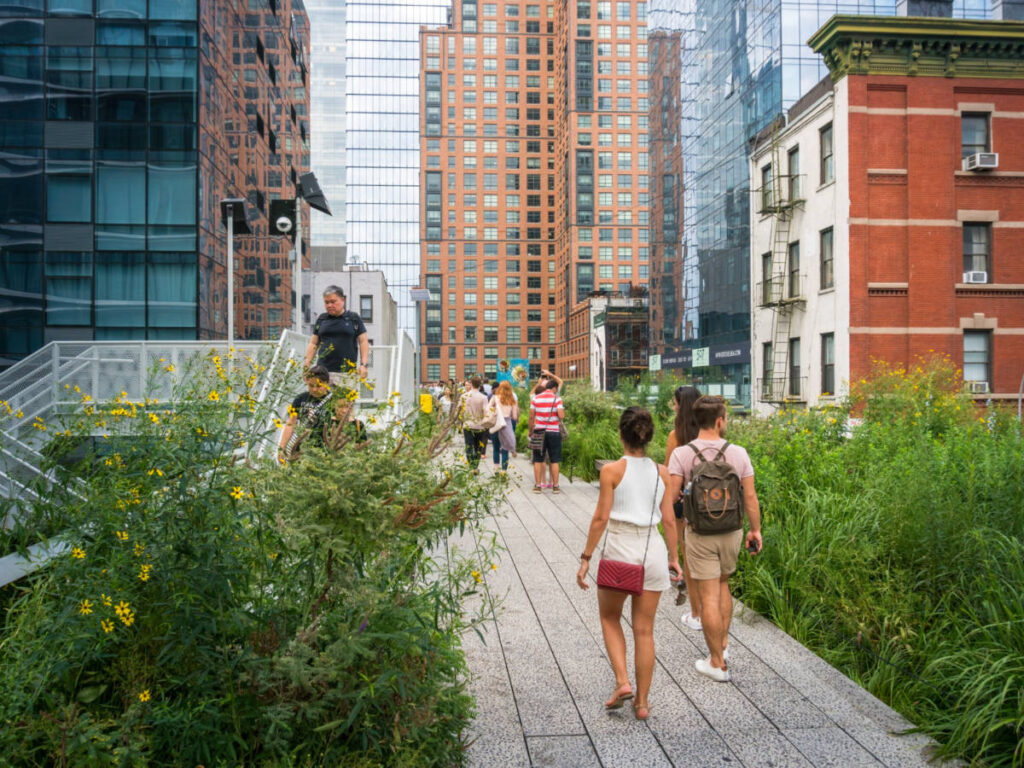 People stroll among New York skyscrapers on the famous pedestrian path called High Line Interim Walkway