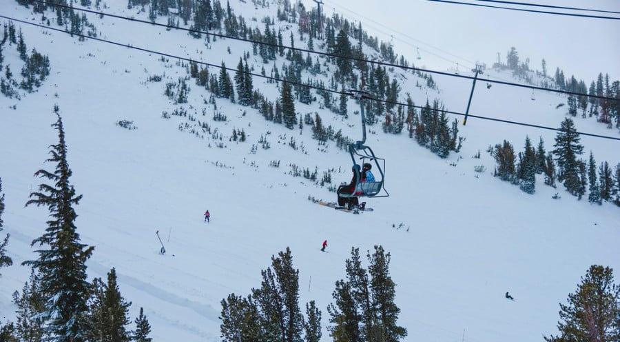 Two snowboarders riding on a ski lift at the snow covered Sugar Bowl Ski Reso.