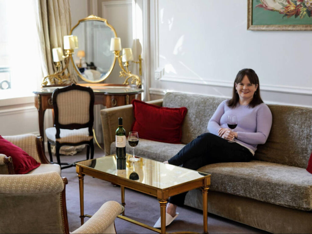The author Rachel Kapelke-Dale sitting on a couch at the Hotel Regina Louvre