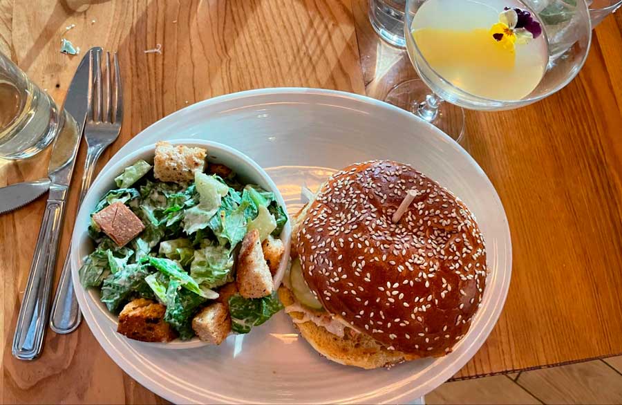 A chicken burger and a glass of cocktail on a table