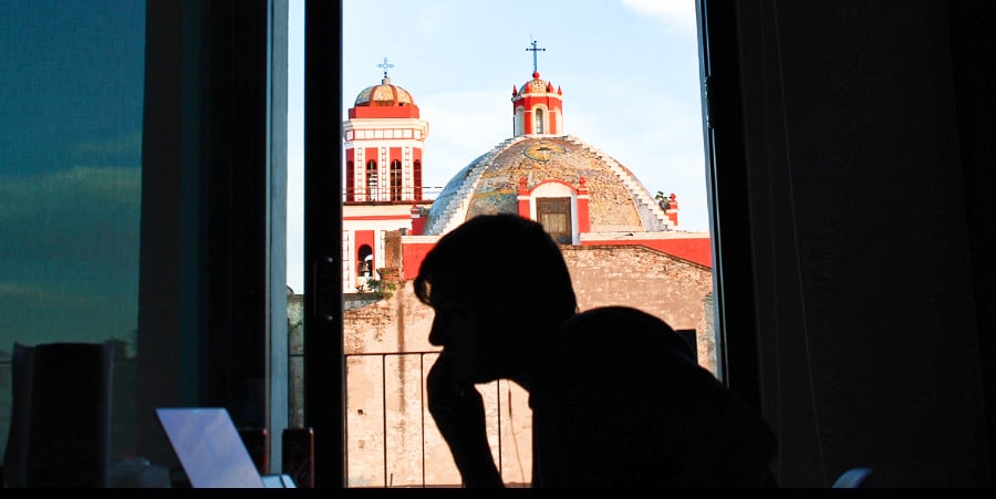 A silhouette of a man in front of the laptop with a top view of the Catholic Church