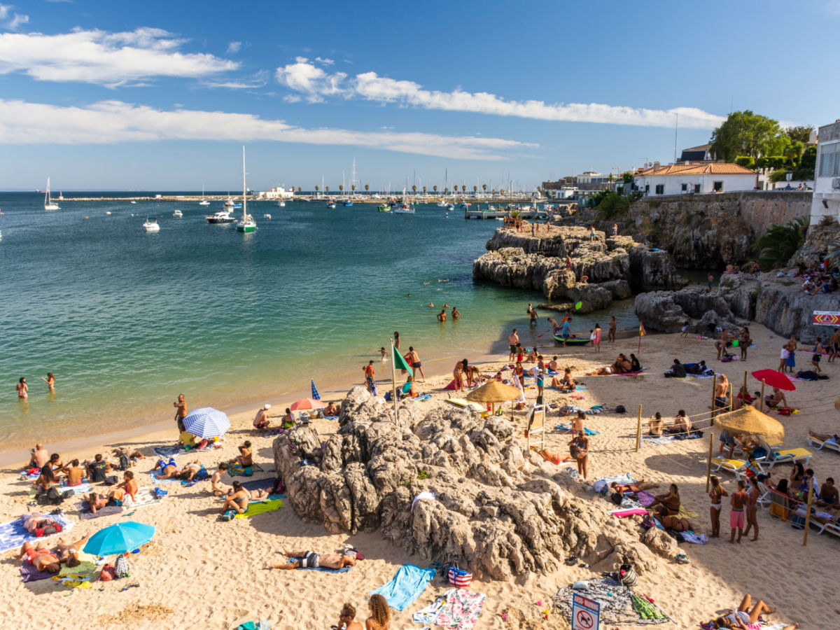 Beach full of locals and tourists on a sunny summer weekend in Cascais