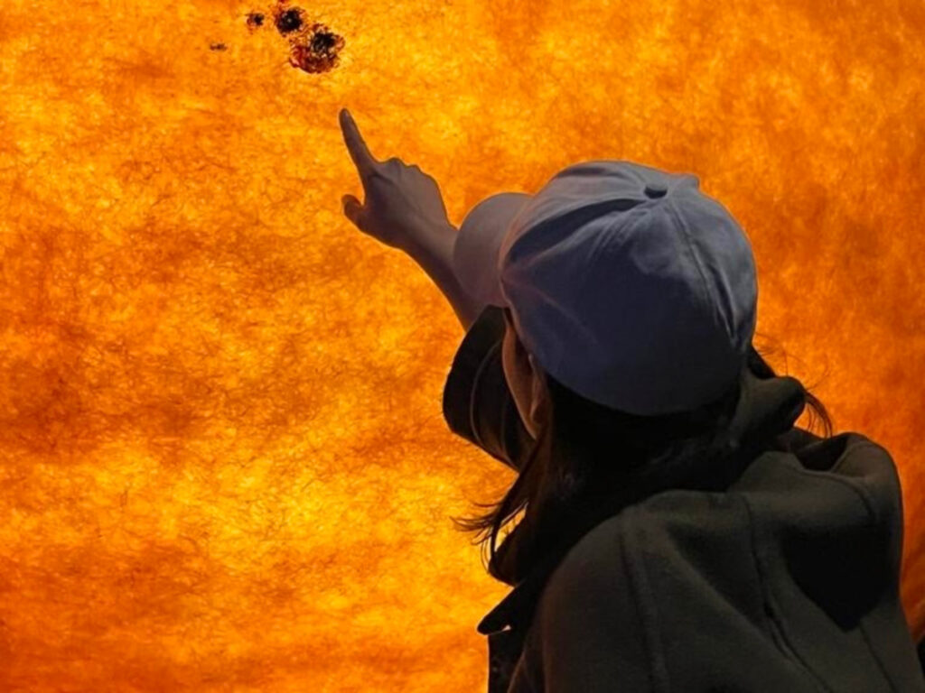 Author Claudicet Pena pointing the Sun Exhibit at the Museum of Science