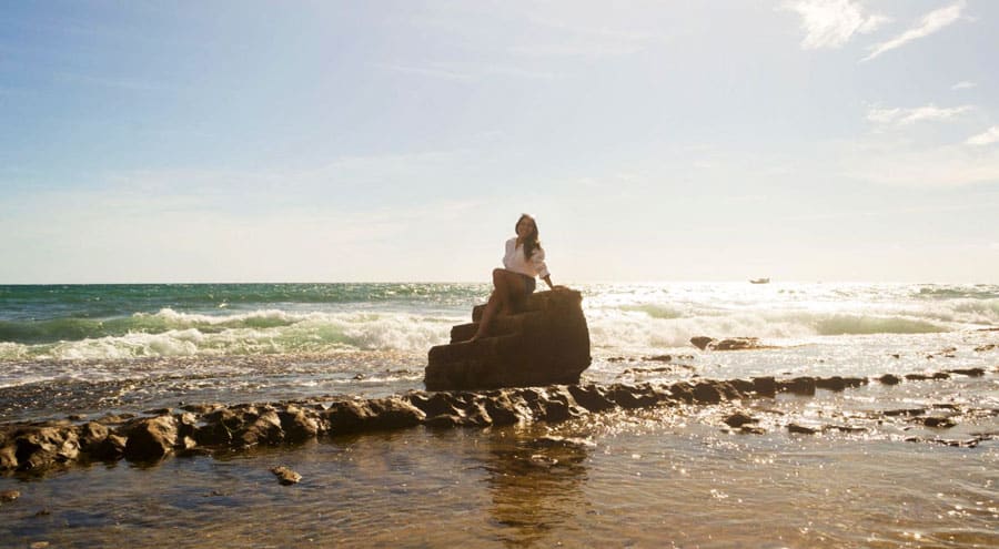 The author sitting on a staircase in Steps Beach during a sunny morning