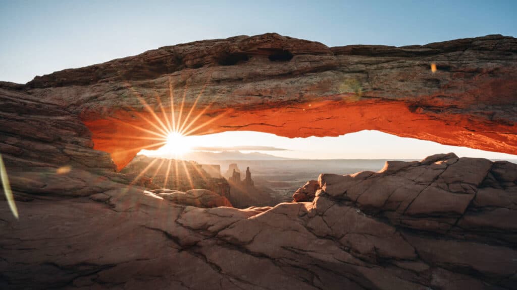 View of the sunrise peeking through the Mesa Arch in Arches National Park