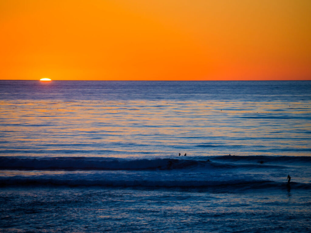 Surfers riding a wave during sunset